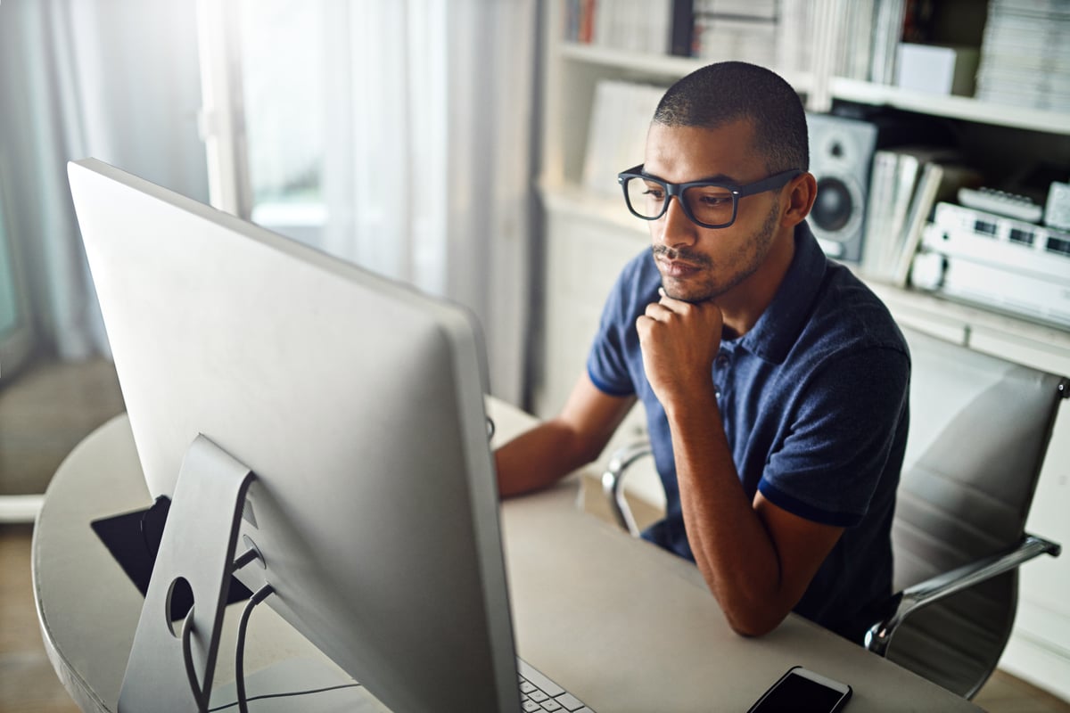 A serious young man working on his computer at home.