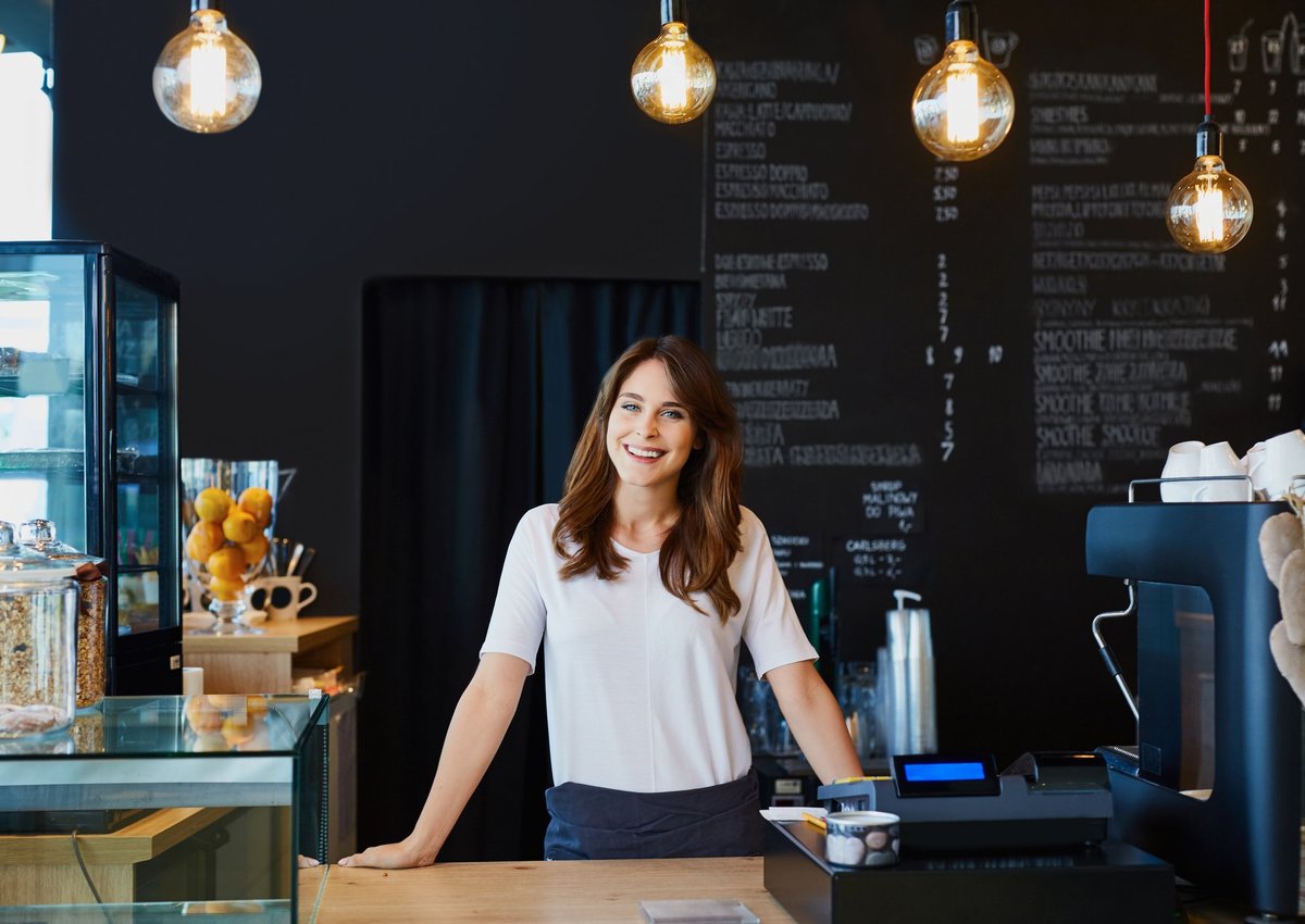 smiling young woman standing behind the counter in a cafe