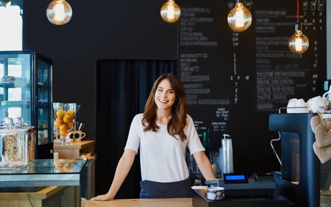 smiling young woman standing behind the counter in a cafe