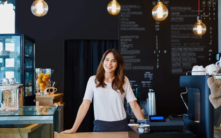 Smiling young woman standing behind counter in cafe