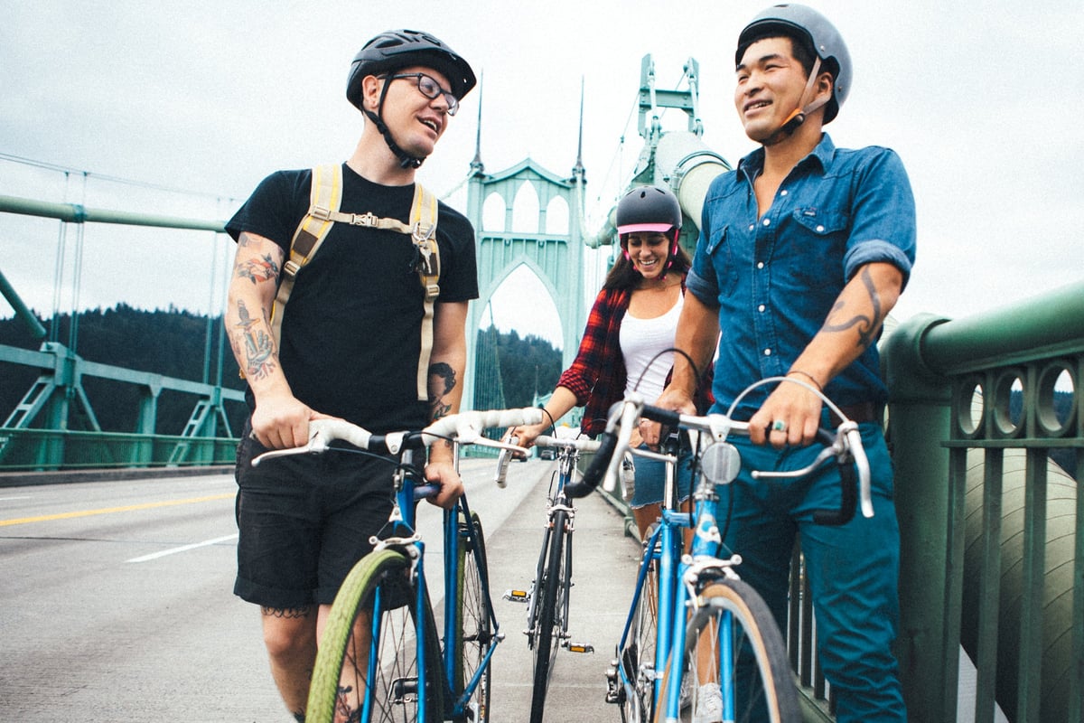 Three people standing next to their bikes and talking while on a bridge in Portland, Oregon.