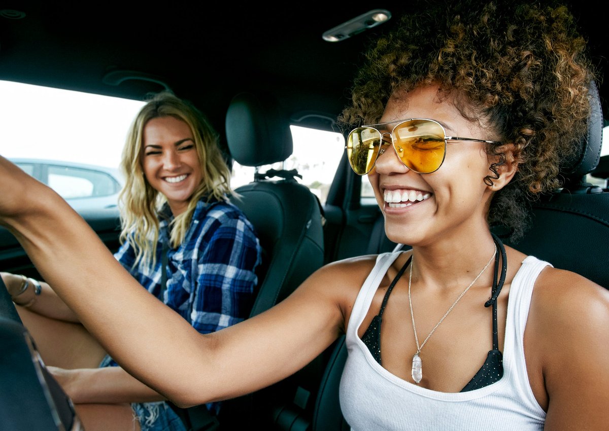 Two smiling people driving in a car.
