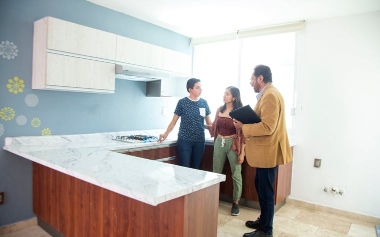 Deux personnes debout dans la cuisine d'une maison à vendre avec un agent immobilier.