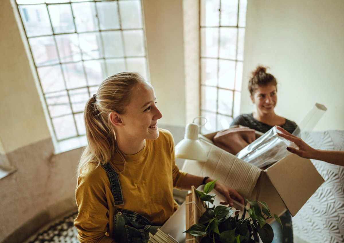 Two young woman moving boxes into a new apartment together.