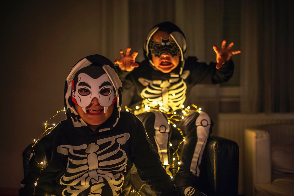 Two little boys in Halloween costumes make scary faces.