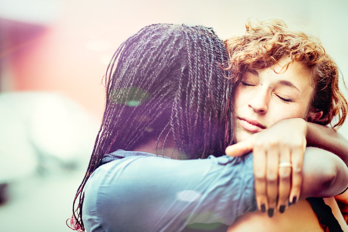 A young woman hugging her girlfriend.