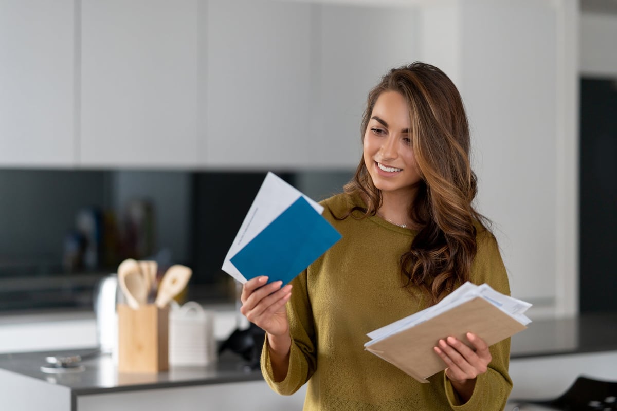 Woman standing in kitchen and holding email.