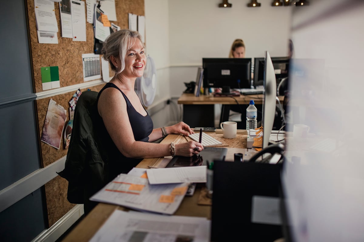 A smiling woman working at her desk in an office.