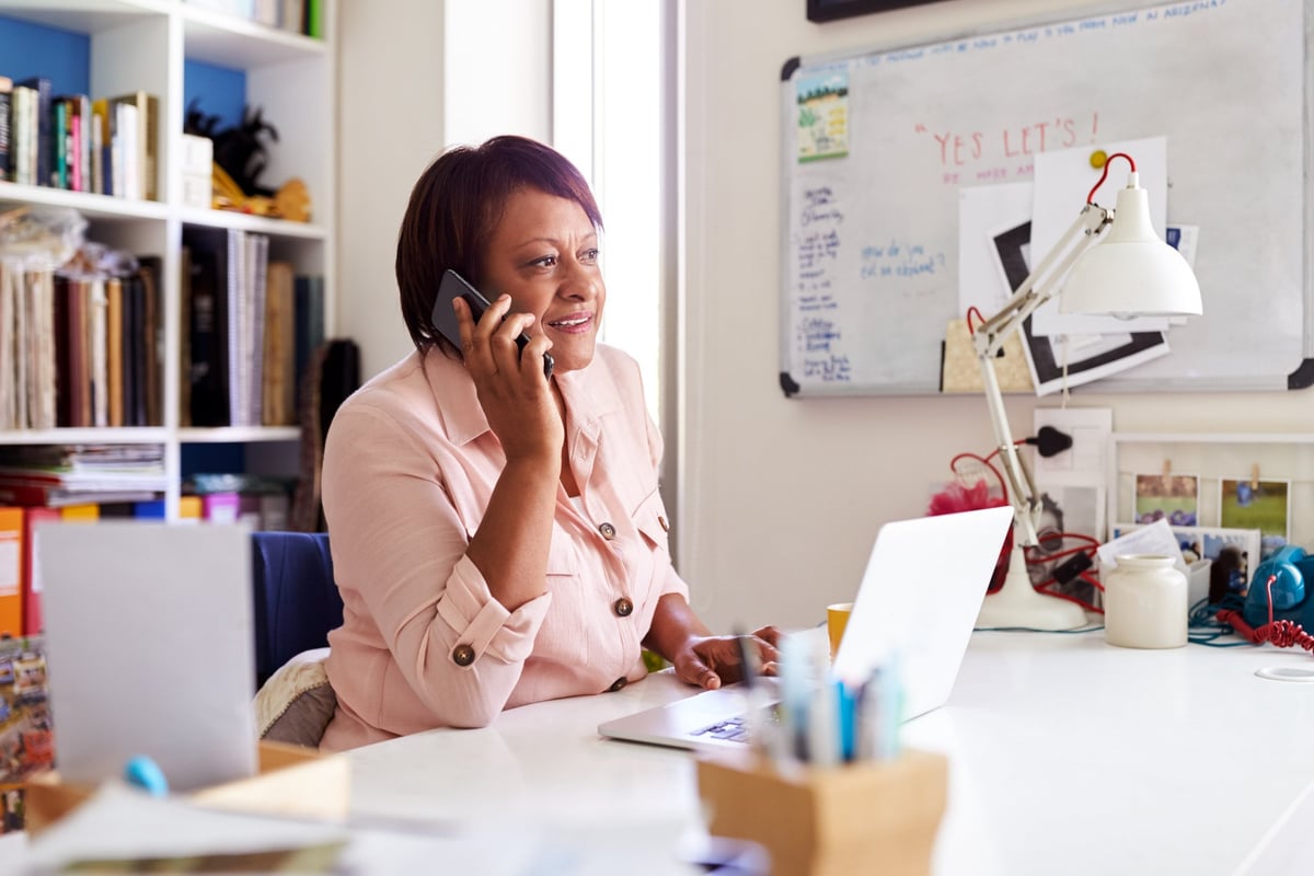 A woman on a phone call while sitting at her desk in her office.
