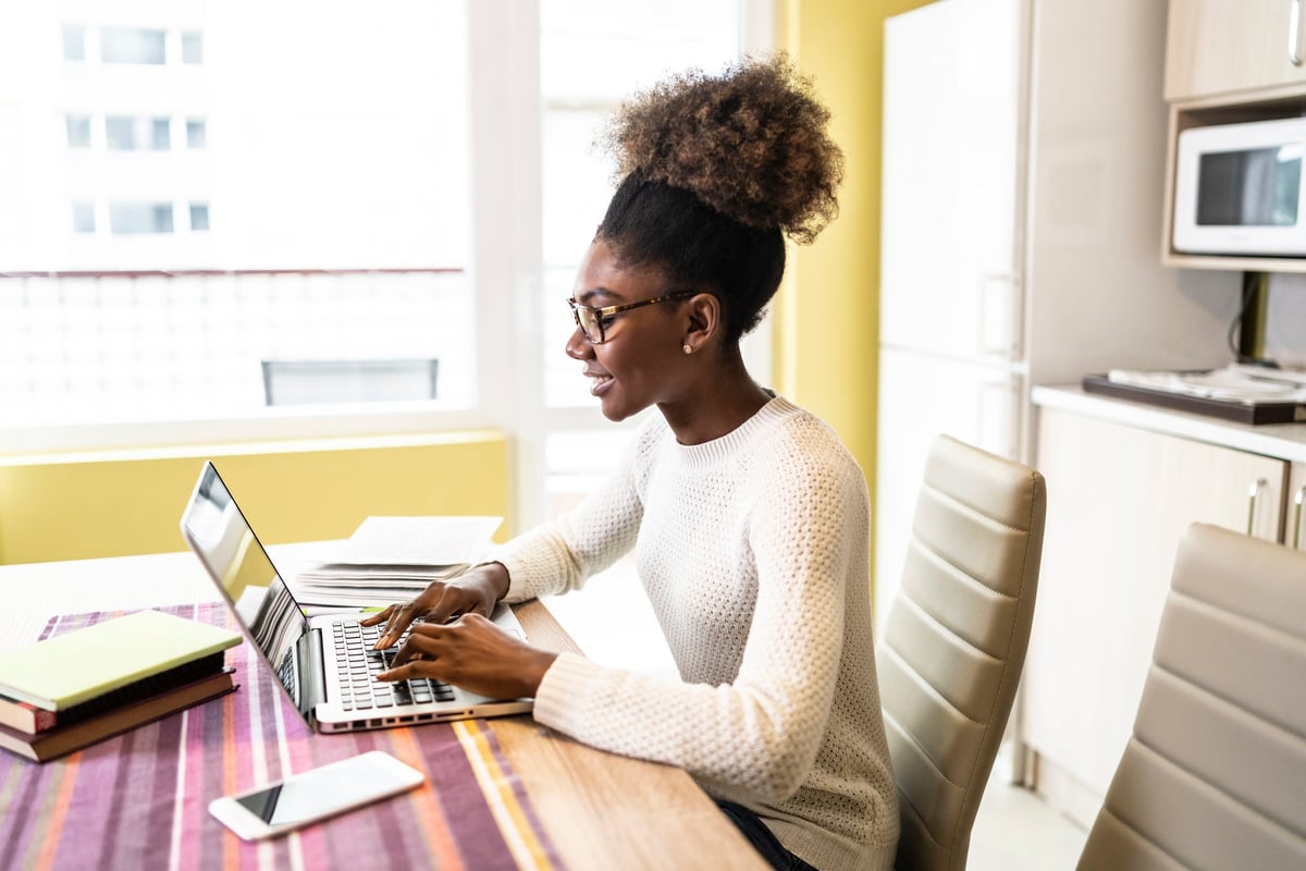 A woman sits at home, looking for a job on her computer.