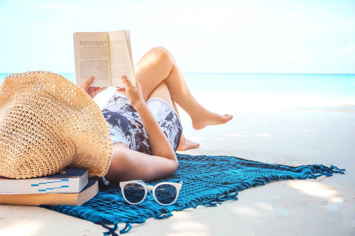 woman reading book on the beach