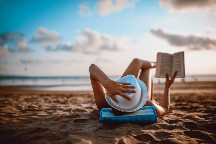 Woman lying on the beach reading a book.