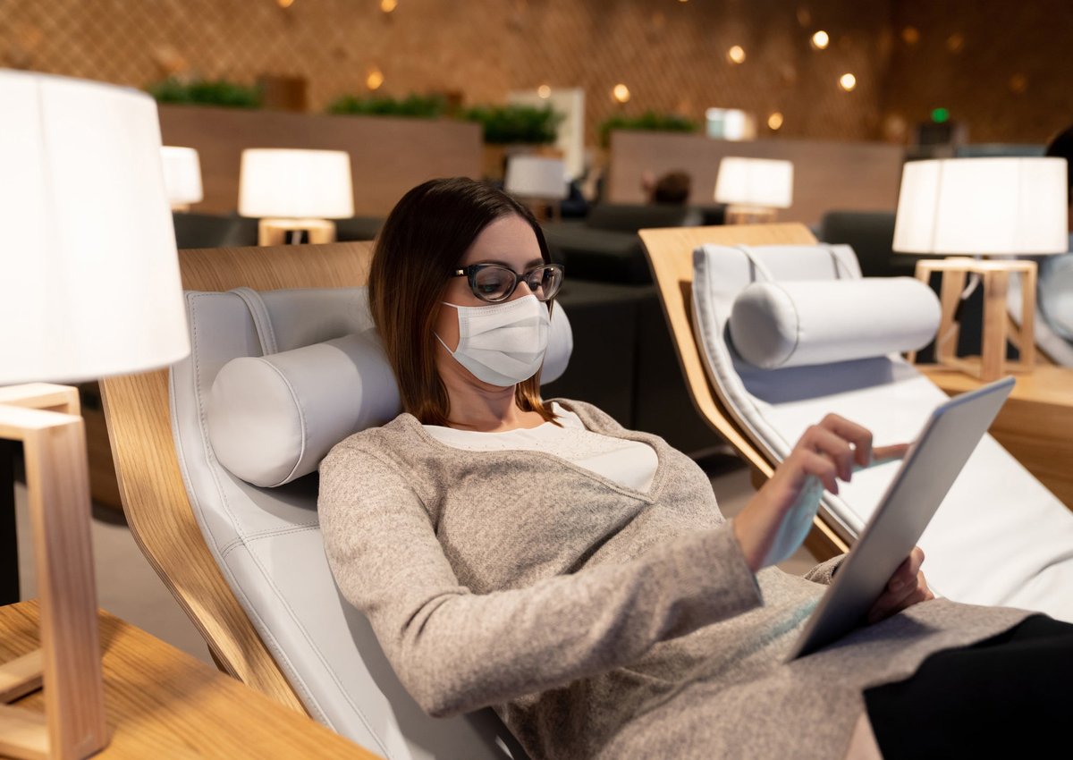 A woman uses her tablet and relaxes in an airport lounge