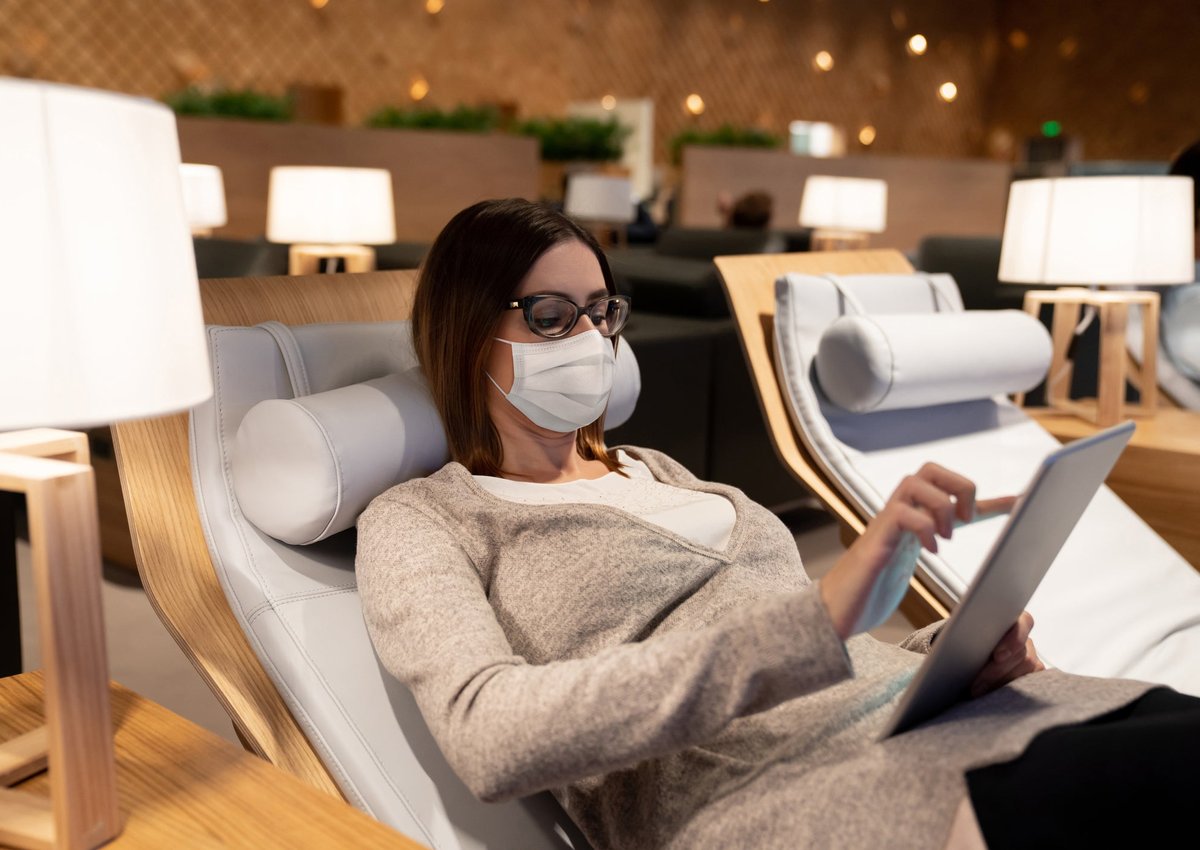 A woman uses her tablet and relaxes in an airport lounge