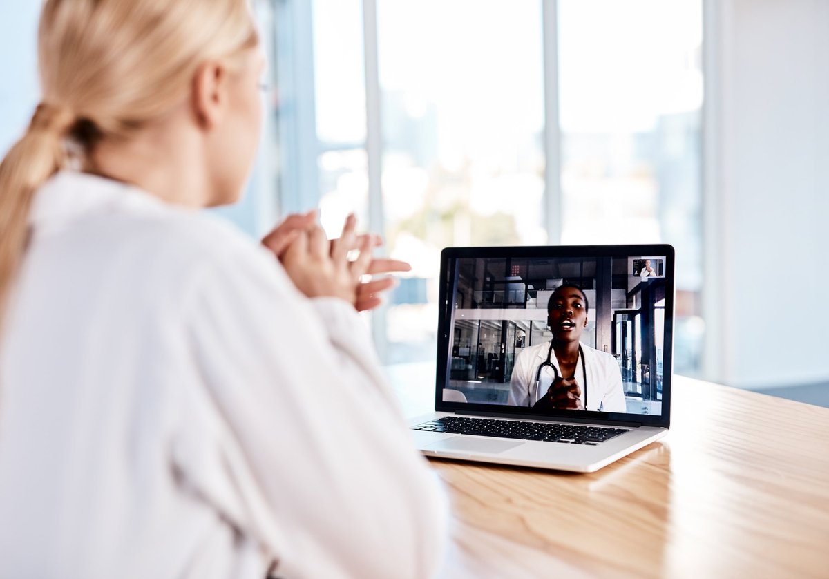 A woman at home speaking with her doctor on a laptop video call.