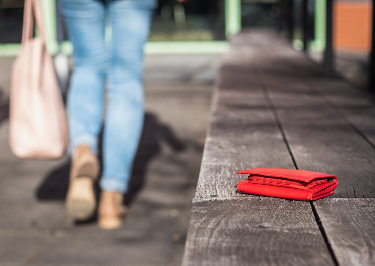 woman walking away from bench with wallet sitting on it