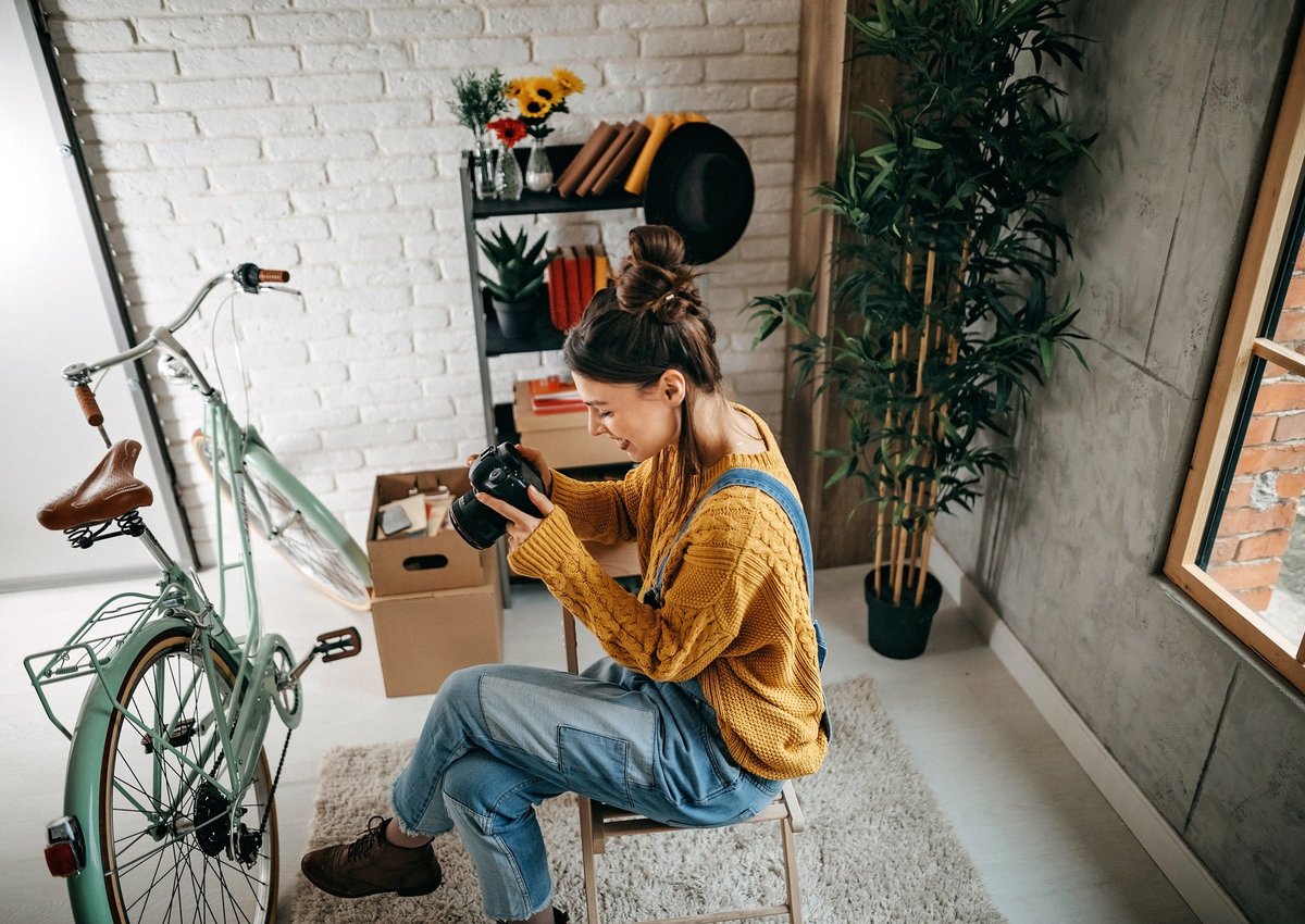 A woman taking photos of her bike and other items in her apartment.