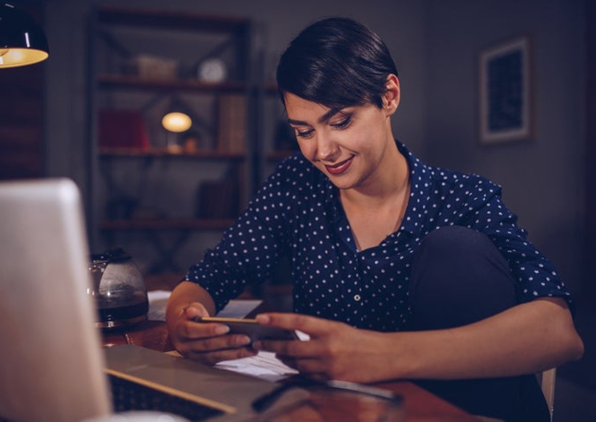 A woman with phone and computer.