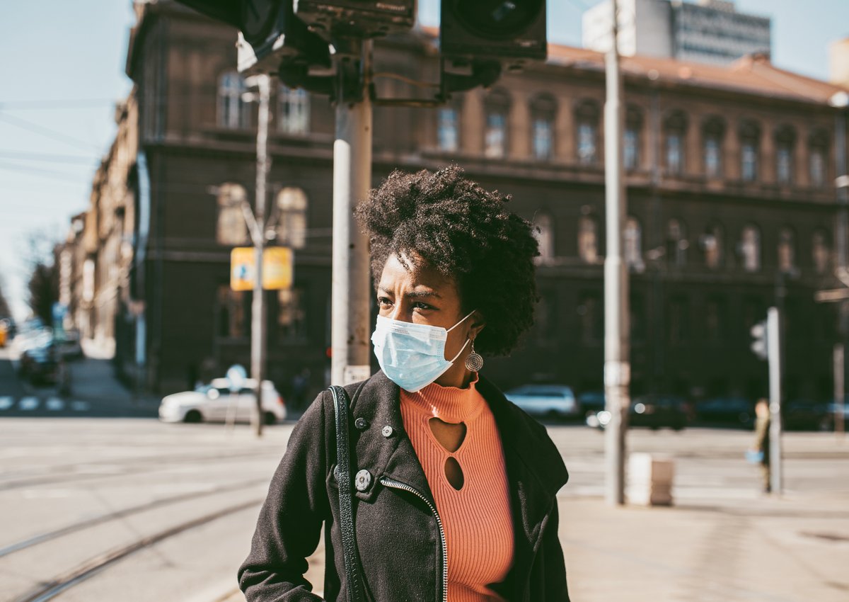 A woman wearing a medical mask walking down the street.