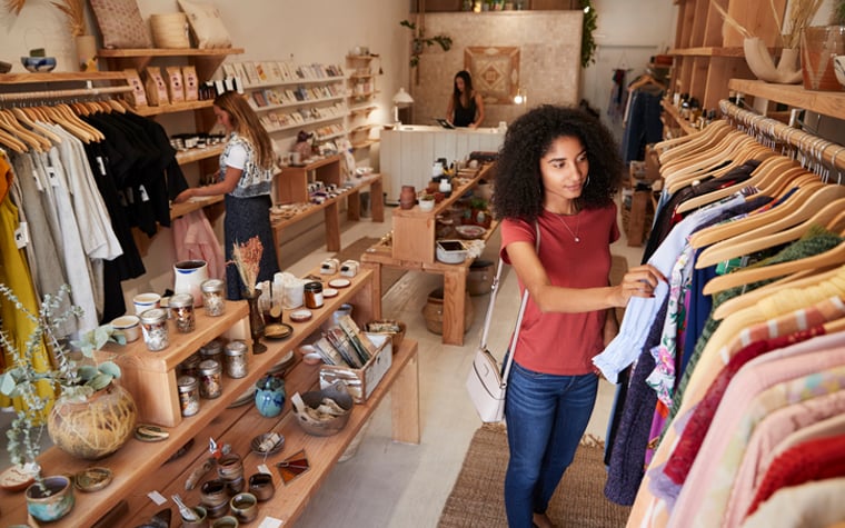 Two women browsing through clothes in a local shop.