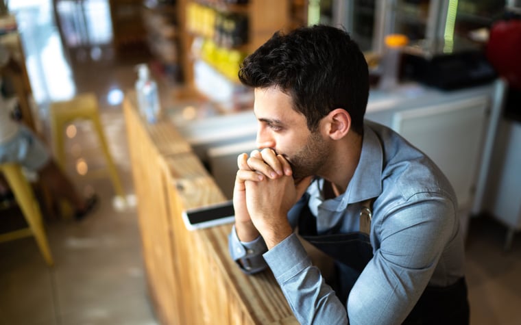 A worried person in an office leaning their chin on their hands.