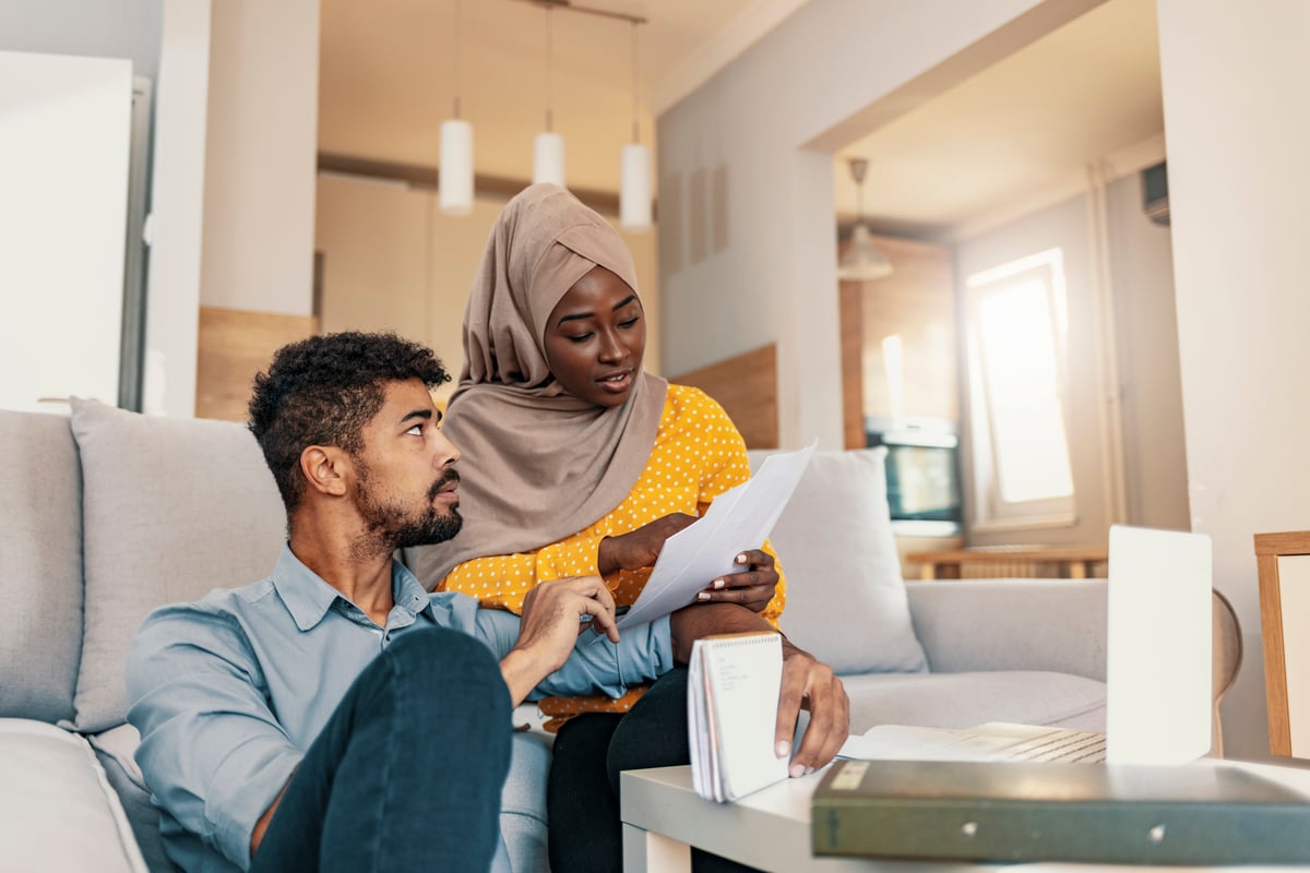 Two people looking over their bills while sitting on their living room couch.