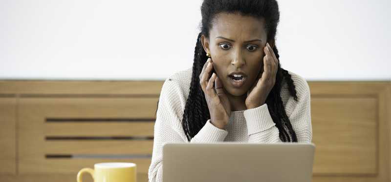 Person opens mouth in surprise while looking at laptop screen.