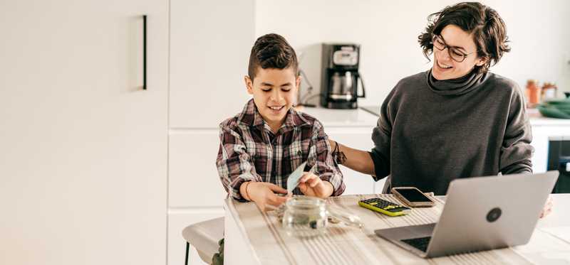 Adult and child are working on savings jar in a kitchen.