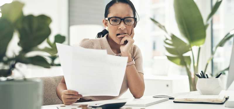 Worried person looking at paperwork in office.