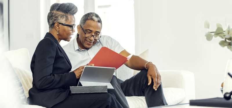Two people sitting on couch and reviewing paperwork.