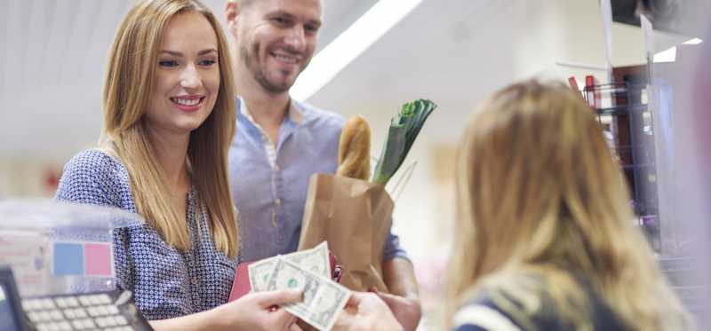 A couple pays cash for groceries.