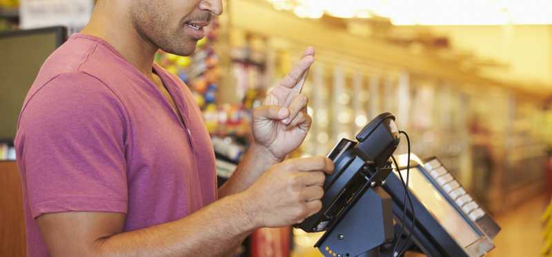 A guy crosses his fingers as he swipes his credit card.