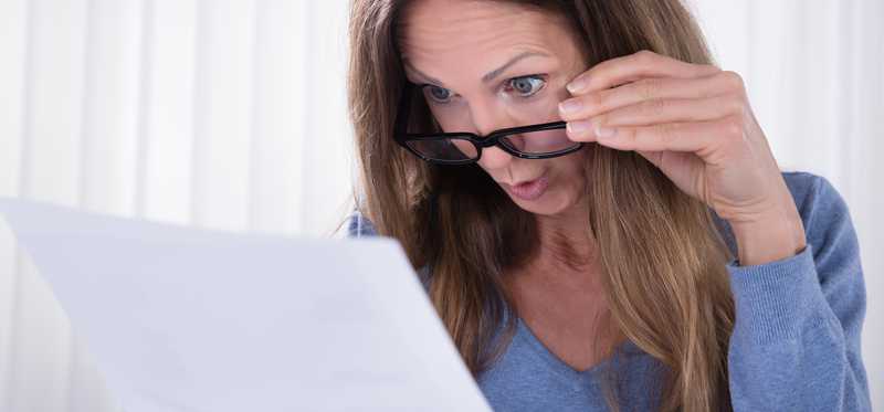 Person lowering glasses to examine a document more closely.