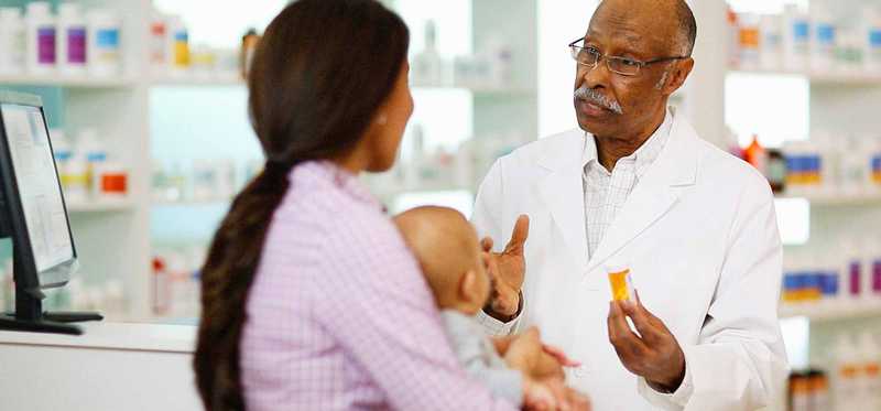 Pharmacist giving medicine to customer and baby.