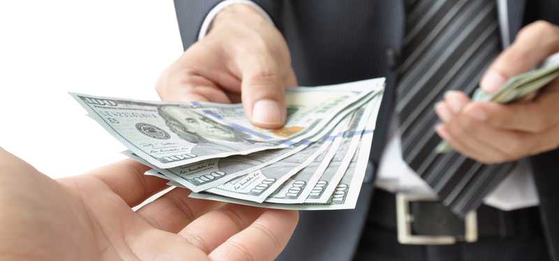 An open palm receiving cash from a man in a suit.
