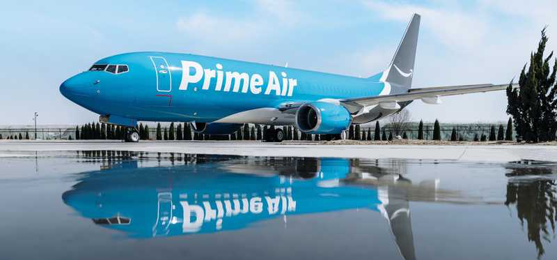 Amazon Prime airplane on tarmac is reflected in large puddle.