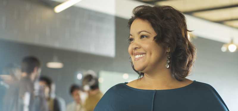 Person smiling while holding a folder in an office.