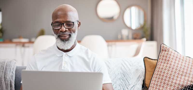 Person smiling while using laptop in a living room.