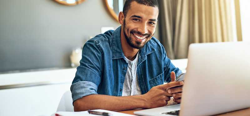 Smiling person in front of computer at home.