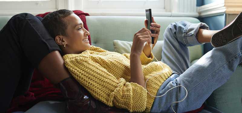 Person lying on couch and looking at phone.