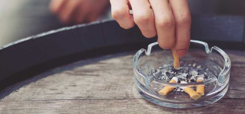 Hand putting out a cigarette in an ashtray.