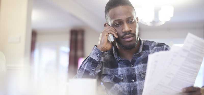 Person talking on phone and holding paperwork.