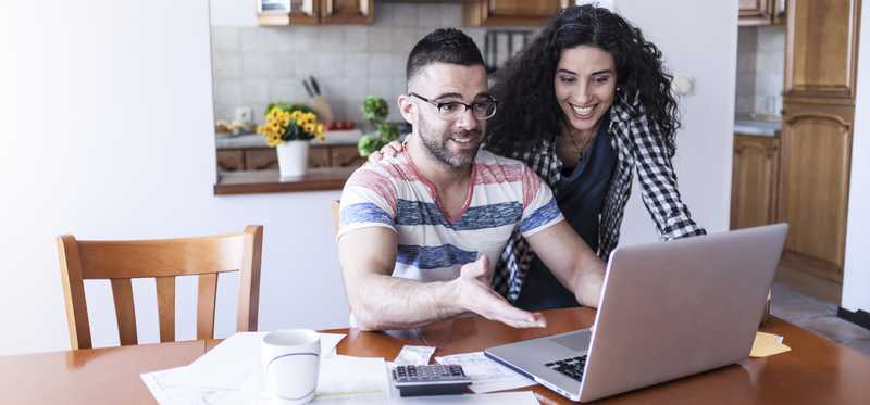 Two people working on their finances in a kitchen.