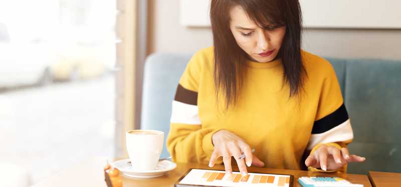 Person reviewing charts with calculator and coffee cup on table.