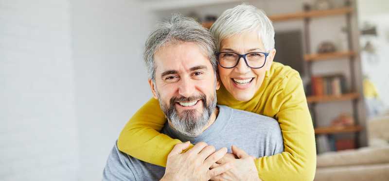 One smiling person has arms wrapped around another smiling person.