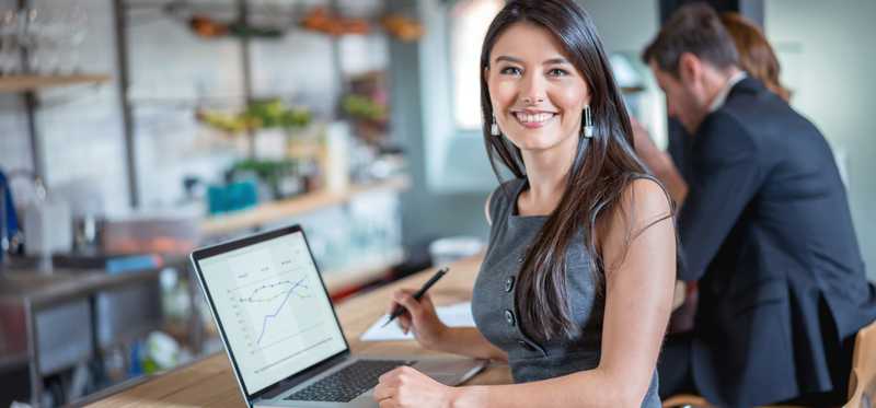 Woman standing at bar in restaurant while working on laptop