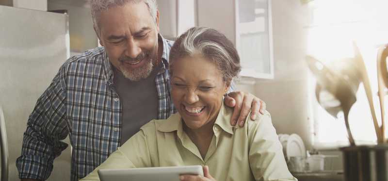 Two people smiling while looking at tablet.
