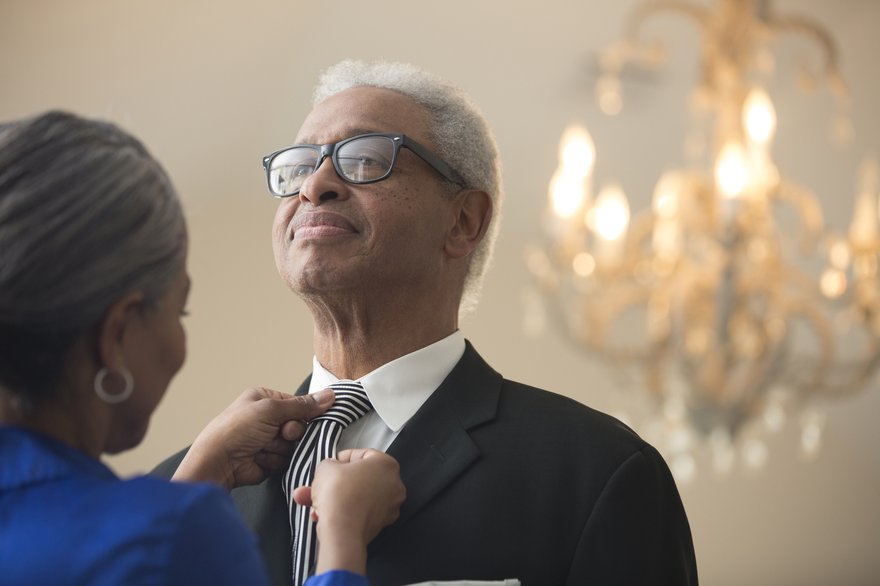 Person helping another person with tying tie.