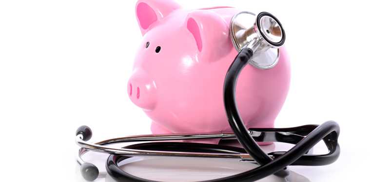A stethoscope listening to the side of a piggy bank.