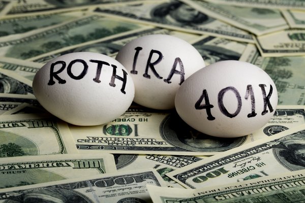 Eggs with IRA, 401K, Roth written on them laying on a pile of cash.